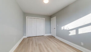 Bedroom with light wood flooring, gray walls, and double-door closet