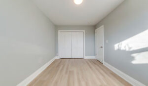 Bedroom with gray walls, light wood floors, and double-door closet