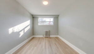 Bedroom with window, radiator heating, gray walls, and light wood flooring
